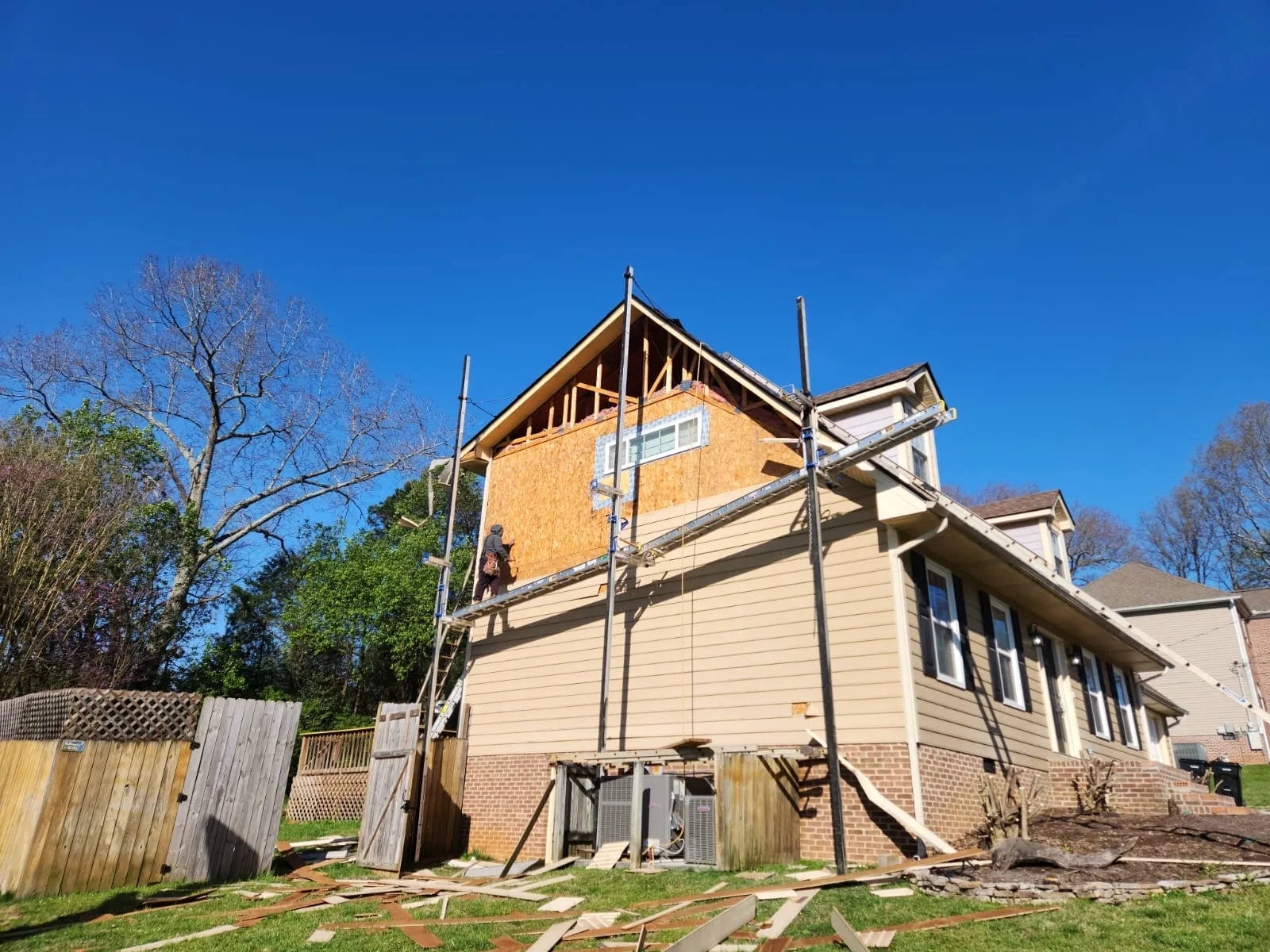 Two-story home with scaffolding and exposed sheathing during siding replacement in Knoxville, TN