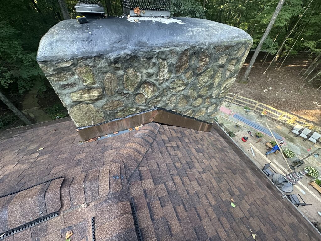 Stone chimney with new copper flashing at the shingle roof junction