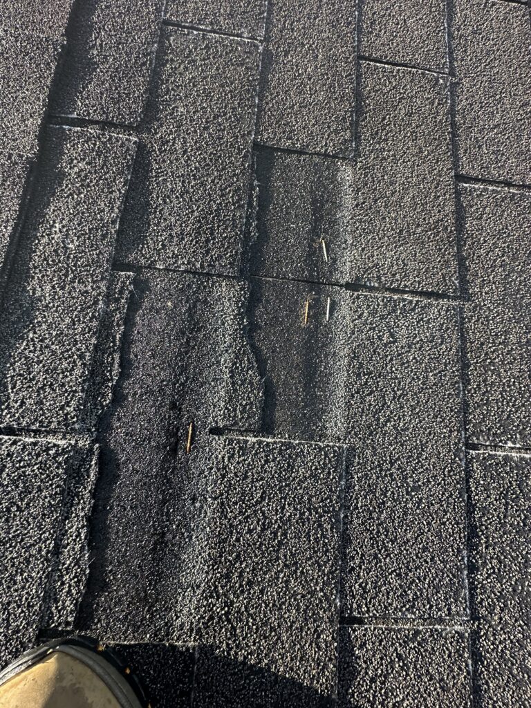 A blown-off shingle showing improper nail placement from a bad roof installation in Knoxville.