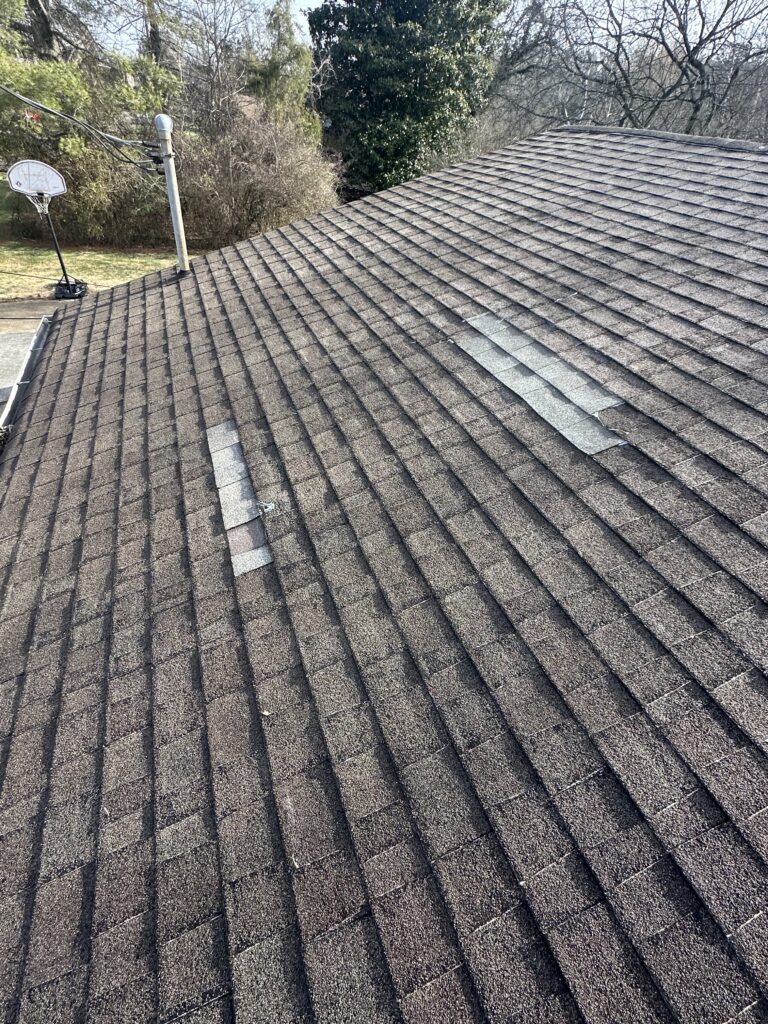 Close-up of an asphalt shingle lifted by wind on a roof in Knoxville, TN.