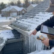 Close-up of a contractor cleaning and sealing a residential downspout to prevent ice gutter problems in Knoxville TN.