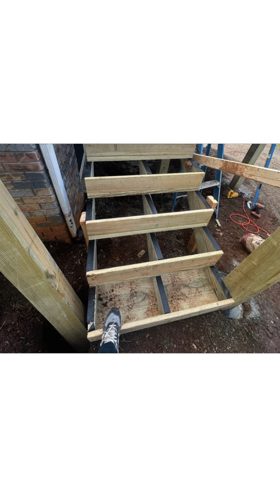 Repairing wood rot at the base of deck stairs caused by ground moisture.
