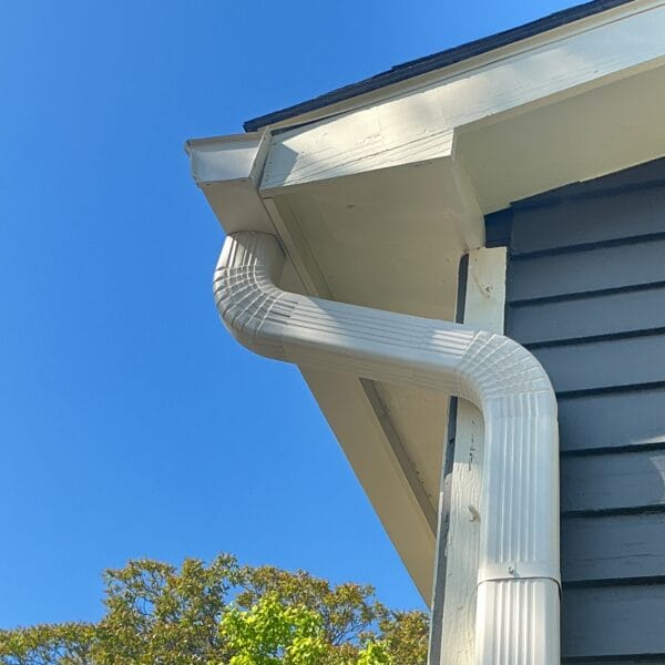 White gutter and downspout elbow at the corner of a navy blue lap siding home in Knoxville, TN