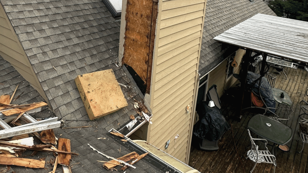 Storm damage on a Knoxville, TN home: siding torn from the wall and debris across the roof and deck
