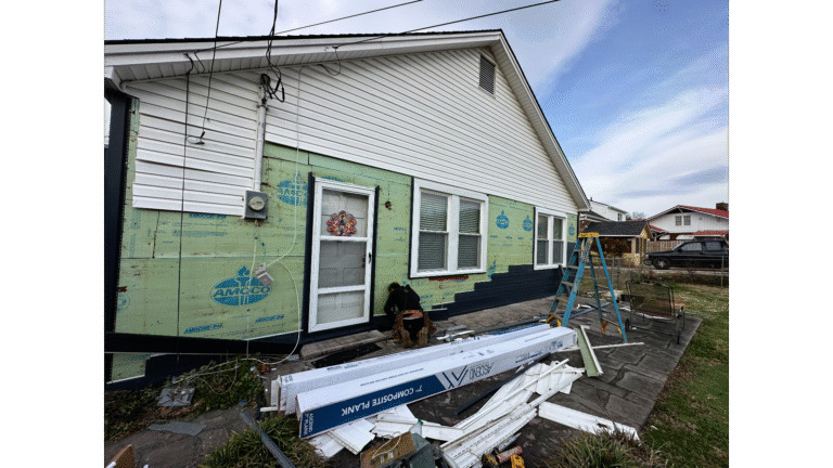 Professional inspection revealing hidden moisture and water damage trapped behind vinyl siding panels.