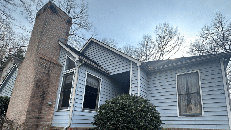 Warped and heat-damaged siding panels on the side of a chimney structure.