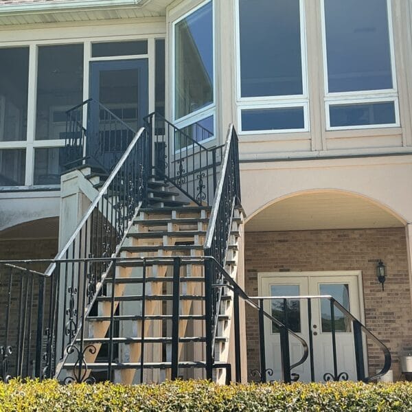 Rear elevation of a home with a screened porch, sunroom windows and an exterior staircase