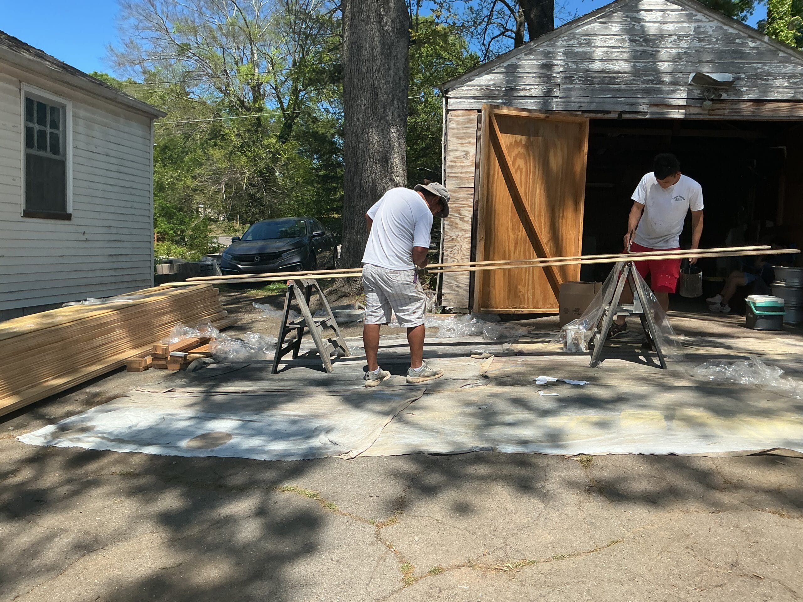 MI crew cutting trim boards on sawhorses with drop cloths down and new material stacked