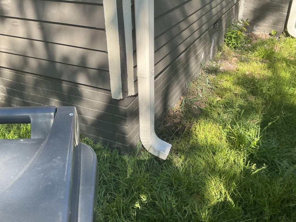 White downspout running down gray lap siding to the lawn on a Knoxville, TN home