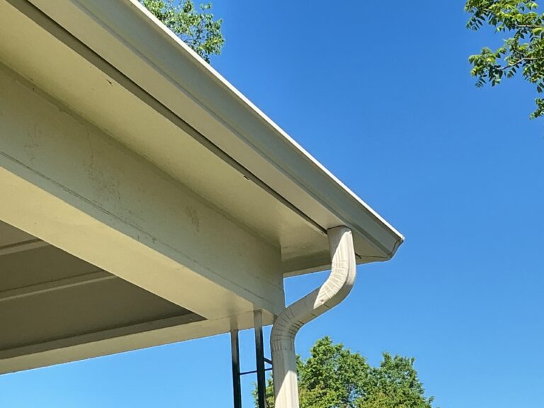 A detailed technical close-up photograph captured during overcast daylight in Knoxville, TN, illustrating an MI Homesiding LLC professional's gloved hand identifying standing water and mosquito larvae in a sagging, brown K-style gutter section.