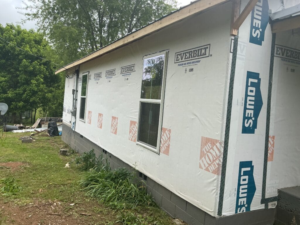 House wrapped in weather-resistant barrier with new windows set, before the siding goes on
