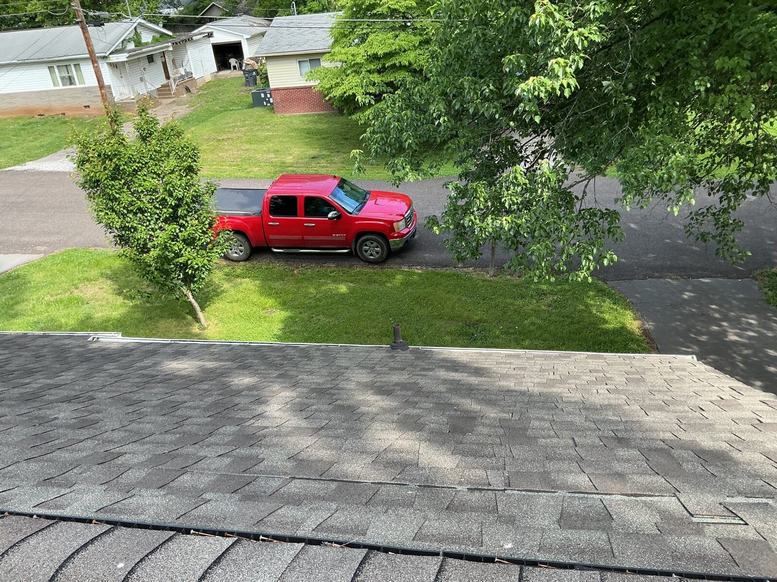 Newly installed asphalt shingle roof seen from the ridge, overlooking a residential street