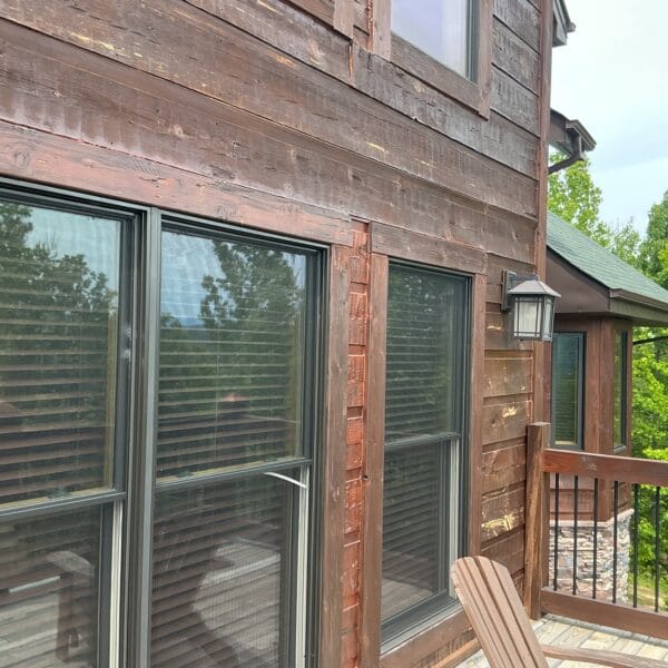 Large residential windows installed in a wood-sided home.