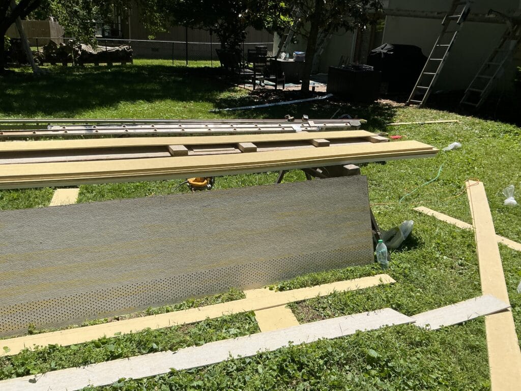 Fiber cement planks and a vented soffit panel staged on sawhorses with a cutting rail