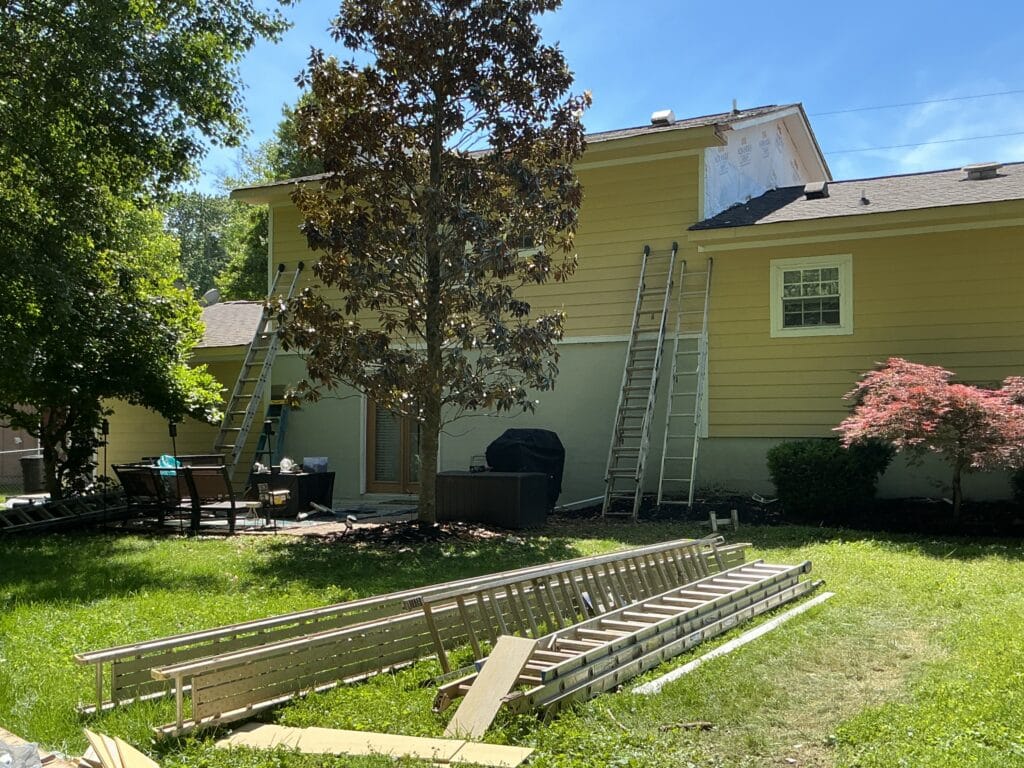 Siding replacement under way on a two-story home, with a dormer stripped back to the housewrap