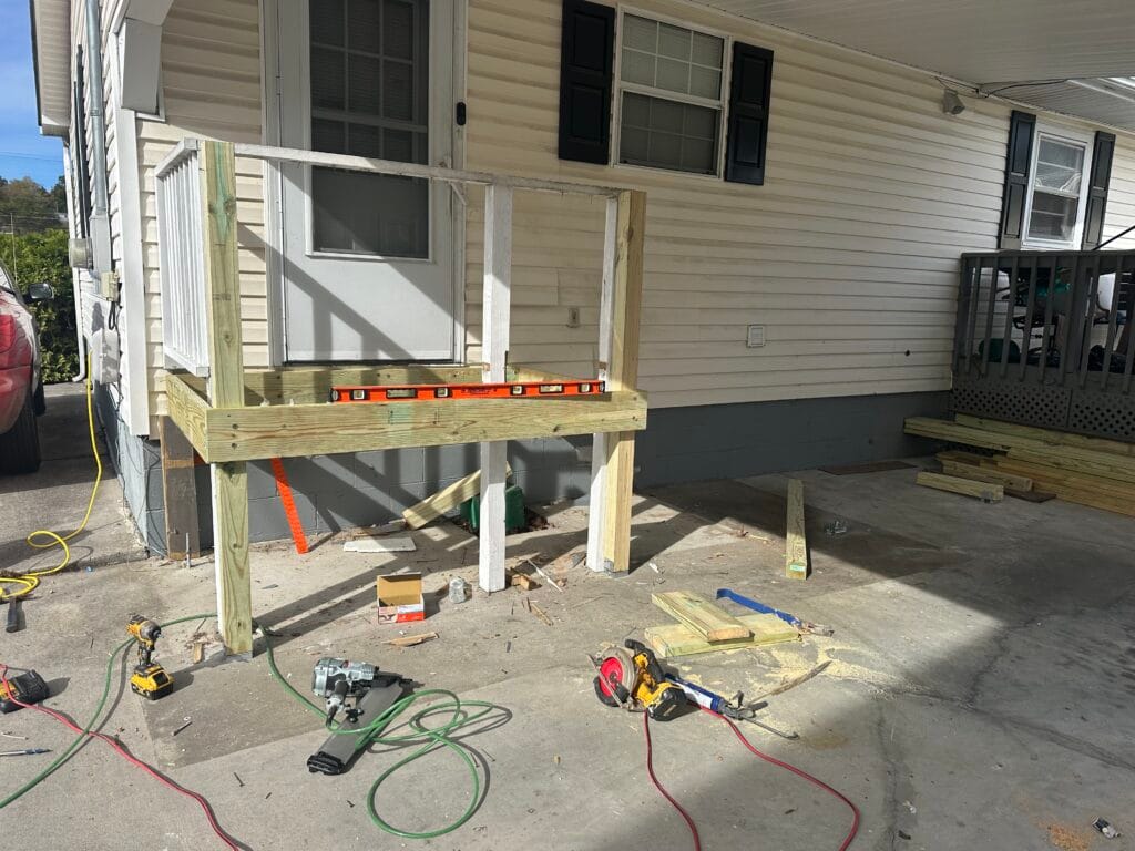 New deck landing going up on treated posts and rim joist, with a level set across the frame before any boards are fastened