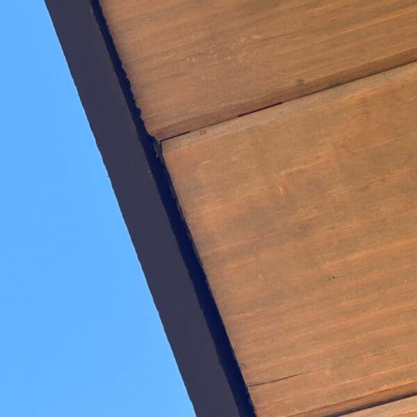 Underside of a cedar soffit and eave against a clear sky in Knoxville, TN