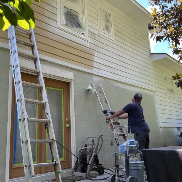 MI Homesiding painter spraying exterior paint from a ladder on a Knoxville, TN home