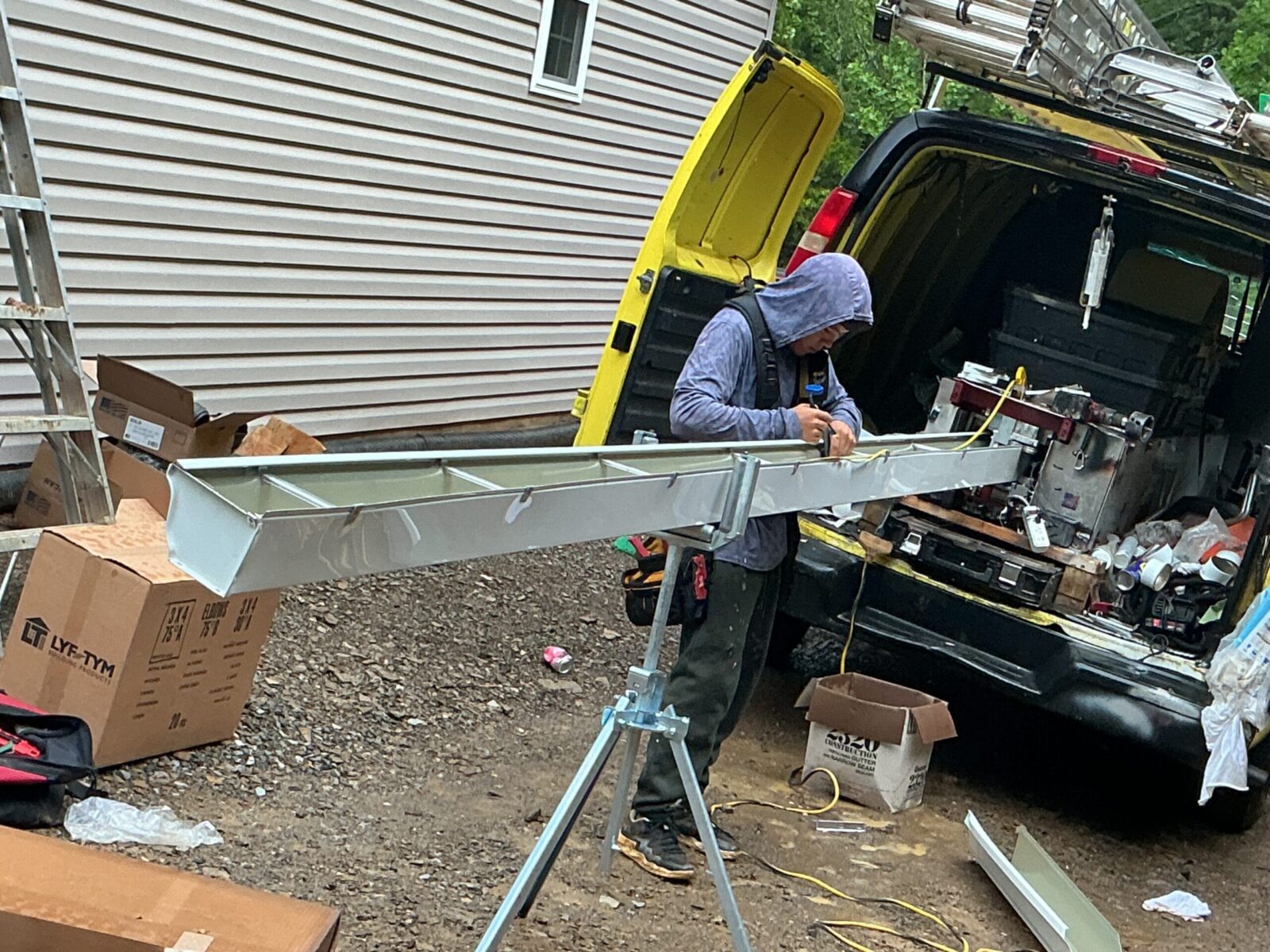 Seamless gutter being formed to length on site from the MI Homesiding work van