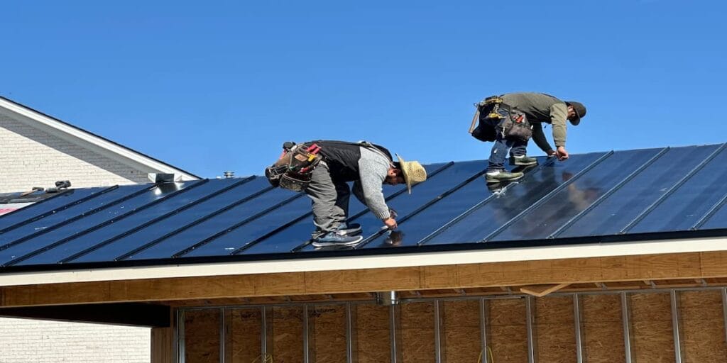 Two installers fastening a standing seam metal roof over exposed decking in Knoxville, TN
