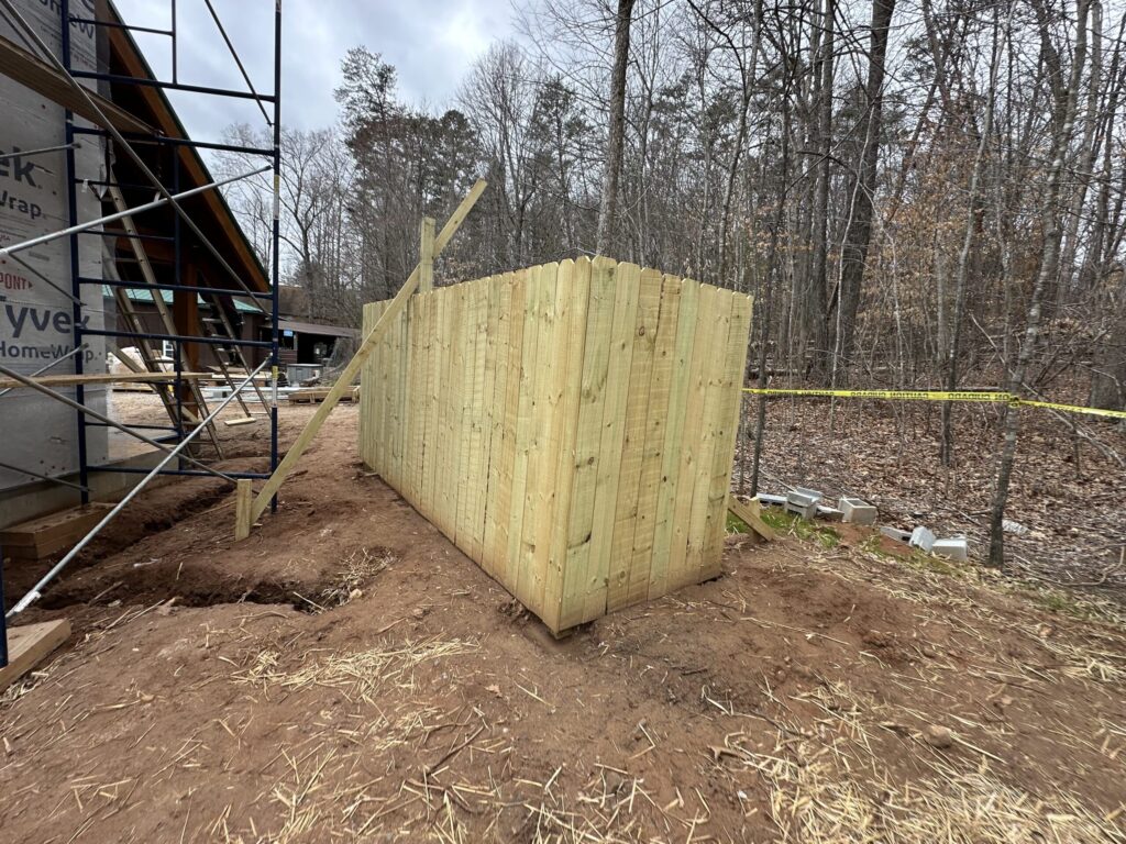 Newly built wood privacy fence with dog-ear pickets and a temporary diagonal brace